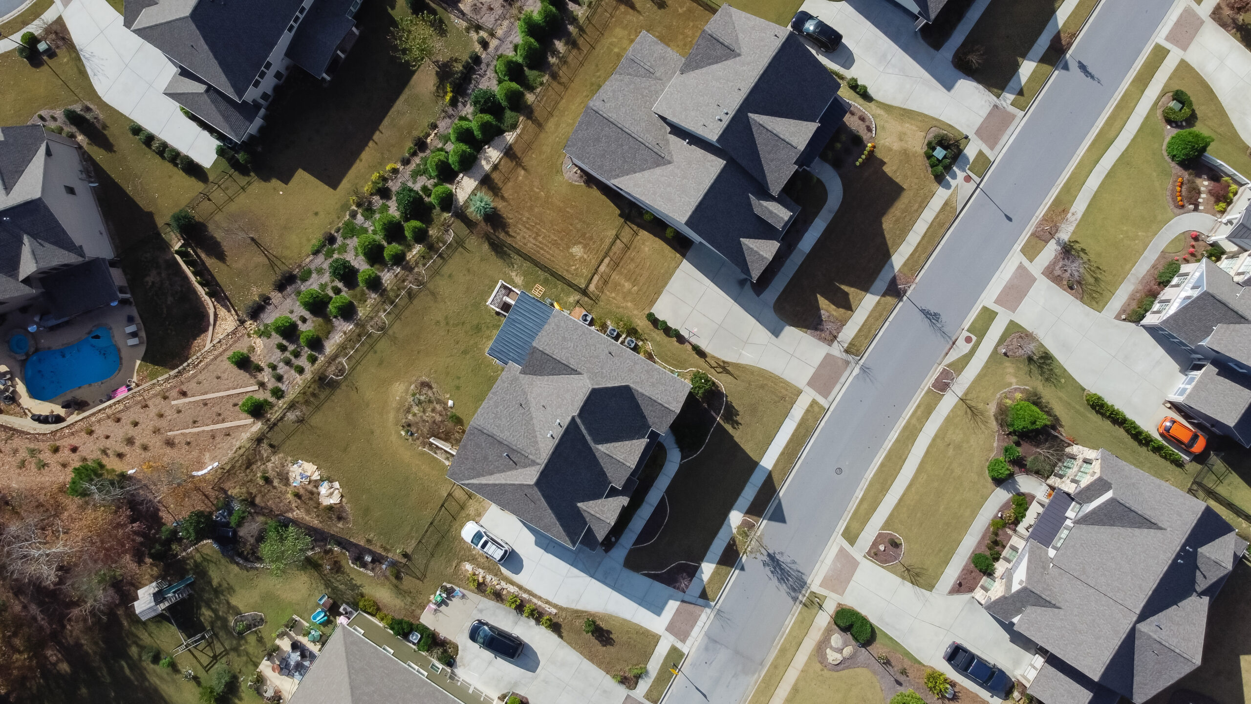90 degree aerial view of brand new two story house with swimming pool and well trimmed yards, front garage in suburban residential neighborhood Flowery Branch, Georgia, US
